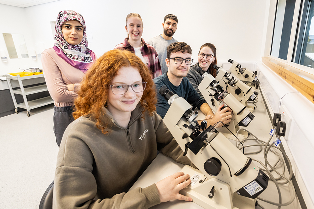 Optometry students posing in front of optometry equipment