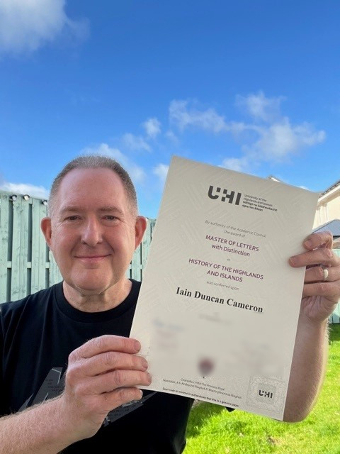 Man smiling and holding a paper with blue sky in the background