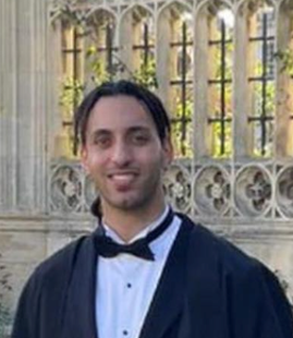 Man wearing a tuxedo and graduation gown. 