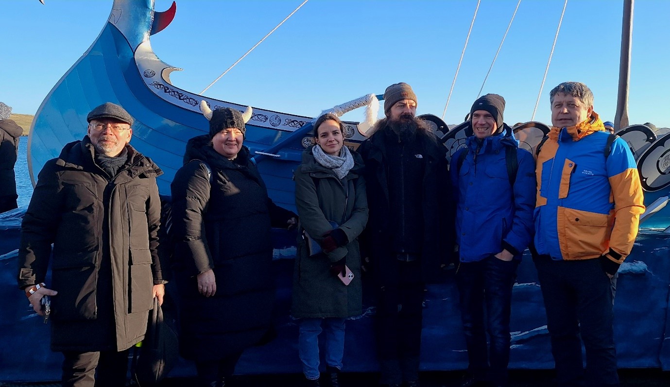 HerInDep team members Kęstutis Zaleckis Aušra Mlinkauskienė Ingrida Povilaitienė Marek Jakoubek Marius Ivaškevičius and Ivan Murin pose in front of the 2024 Lerwick UpHellyAa longship Photo Credit Dr A Lind