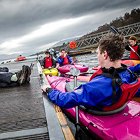 People sitting in Kayaks next to a jetty