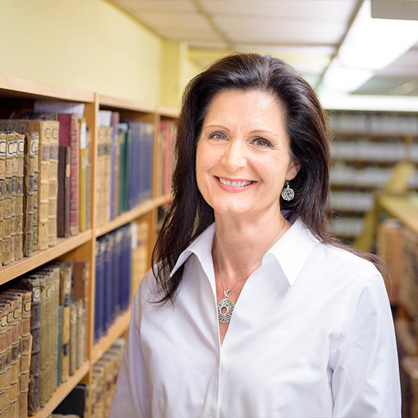 Graduate Theresa in the library alongside historical books